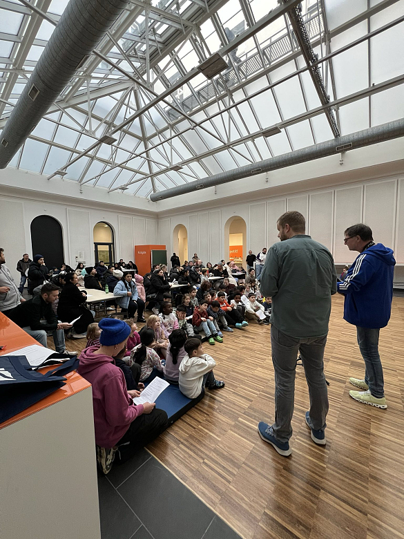 Herr Thielbahr und Herr Schmidt mit Kindern beim gemeinsamen Singen in der Mensa